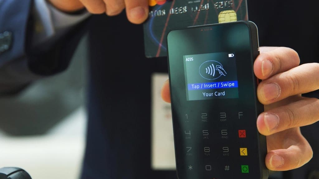 Client réglant un achat sans contact sur un terminal de paiement mobile tenu par le commerçant