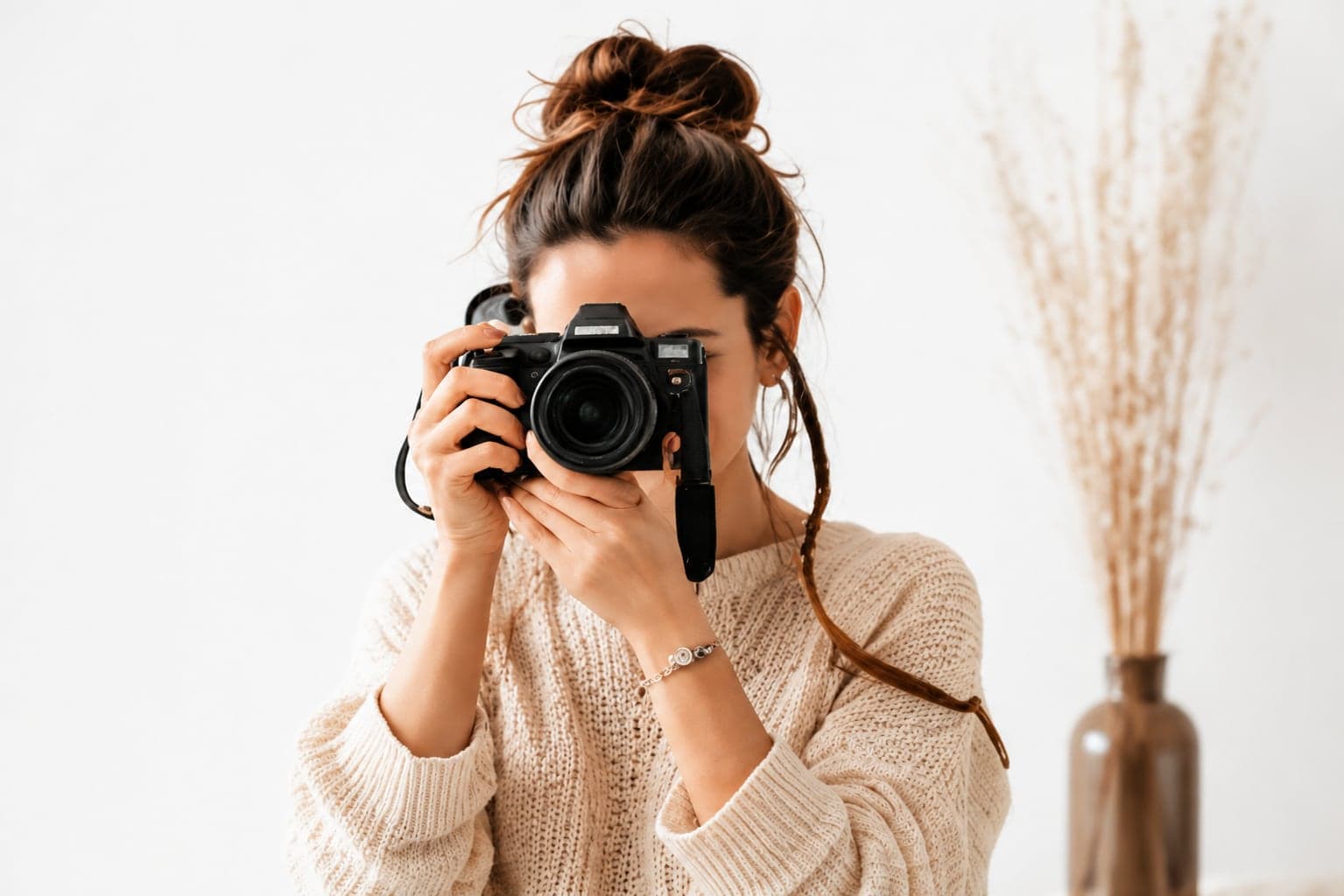 Une photographe cadre au viseur de son appareil, dans un studio